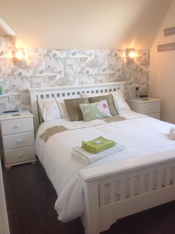 Cleasewood Guest House في غريت يورماوث: غرفة نوم مع سرير أبيض كبير مع زهور على الحائط