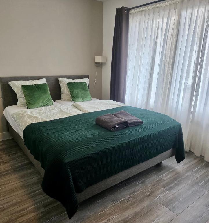 a bedroom with a bed with green sheets and a window at Beijerse inn in Nieuw-Beijerland