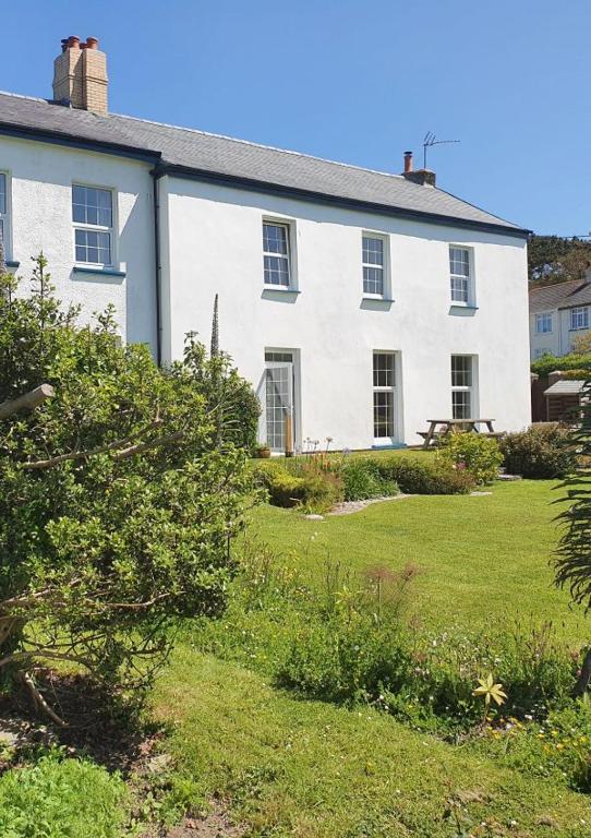 a large white house with a grass yard at Old Vicarage Mortehoe Near Woolacombe 2 x sleeps 4 and 1 x sleeps 10 cottages in Mortehoe