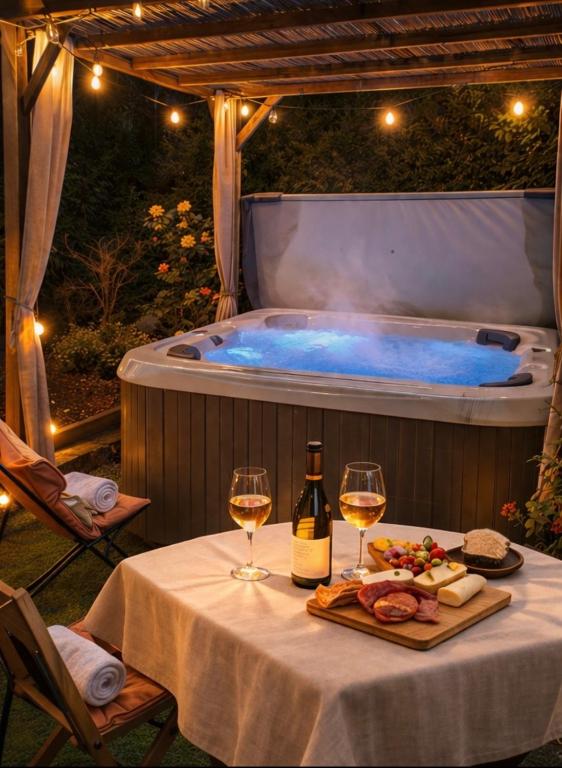 a table with two glasses of wine and a hot tub at L'Impasse en Duo, appartement cosy 2 personnes avec SPA extérieur privé in Munster