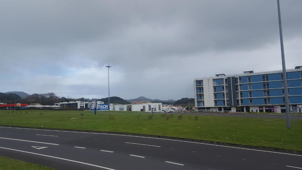 a city street with a building and a field of grass at Apartamento Vista Deslumbrante in Ponta Delgada