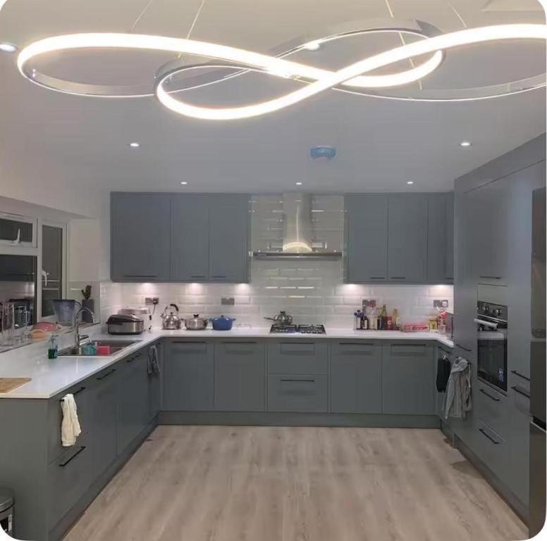 a kitchen with gray cabinets and a large chandelier at Bushy Hill Drive in Guildford in Guildford