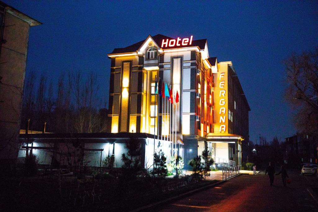 ein Hotelgebäude mit einem Schild daran bei Nacht in der Unterkunft Fergana hotel in Fargʻona