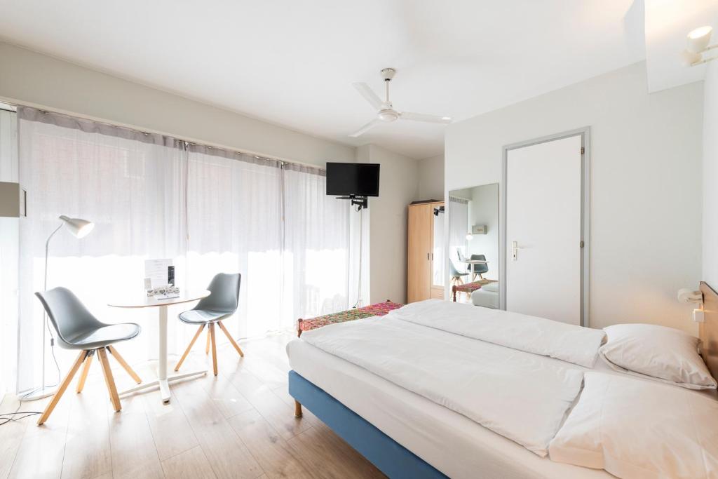 a bedroom with a bed and a table and chairs at Hotel Atlantico self check-in in Lugano