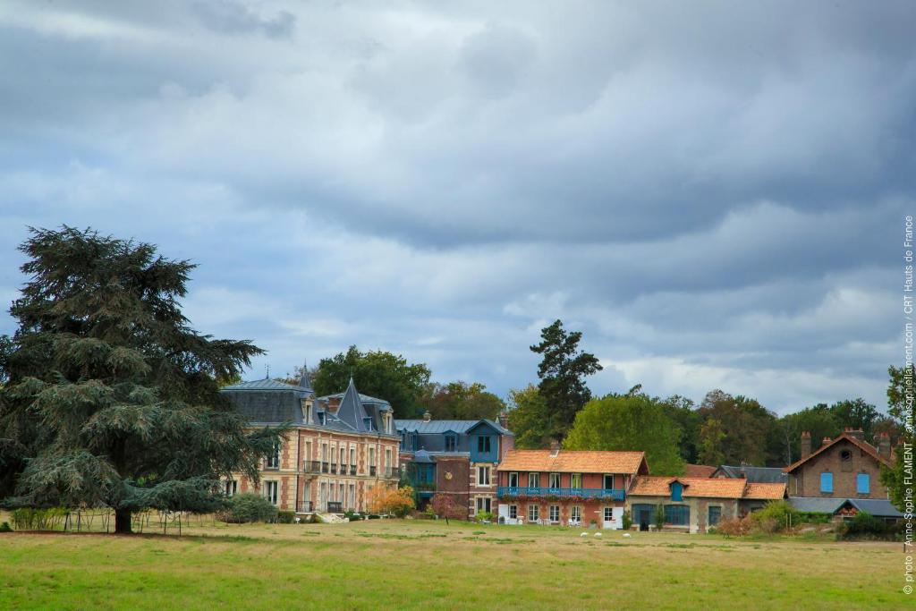 a group of houses in a field with a tree at Chateau le Quesnoy in Chevrières