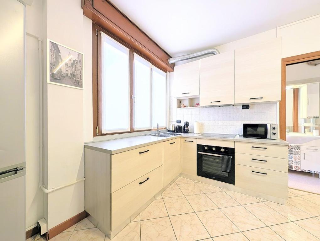 a kitchen with white cabinets and a large window at Popi House in Menaggio