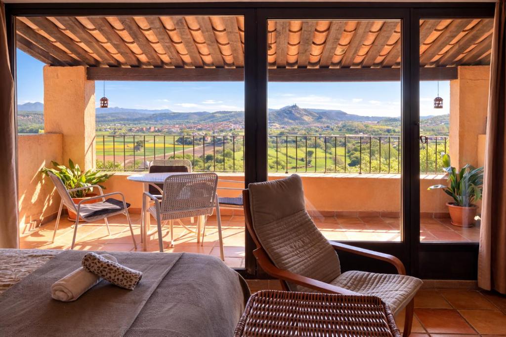 a room with a bed and chairs and a large window at Loft con chimenea y terraza con vistas - Cal Caterino in Montsonis