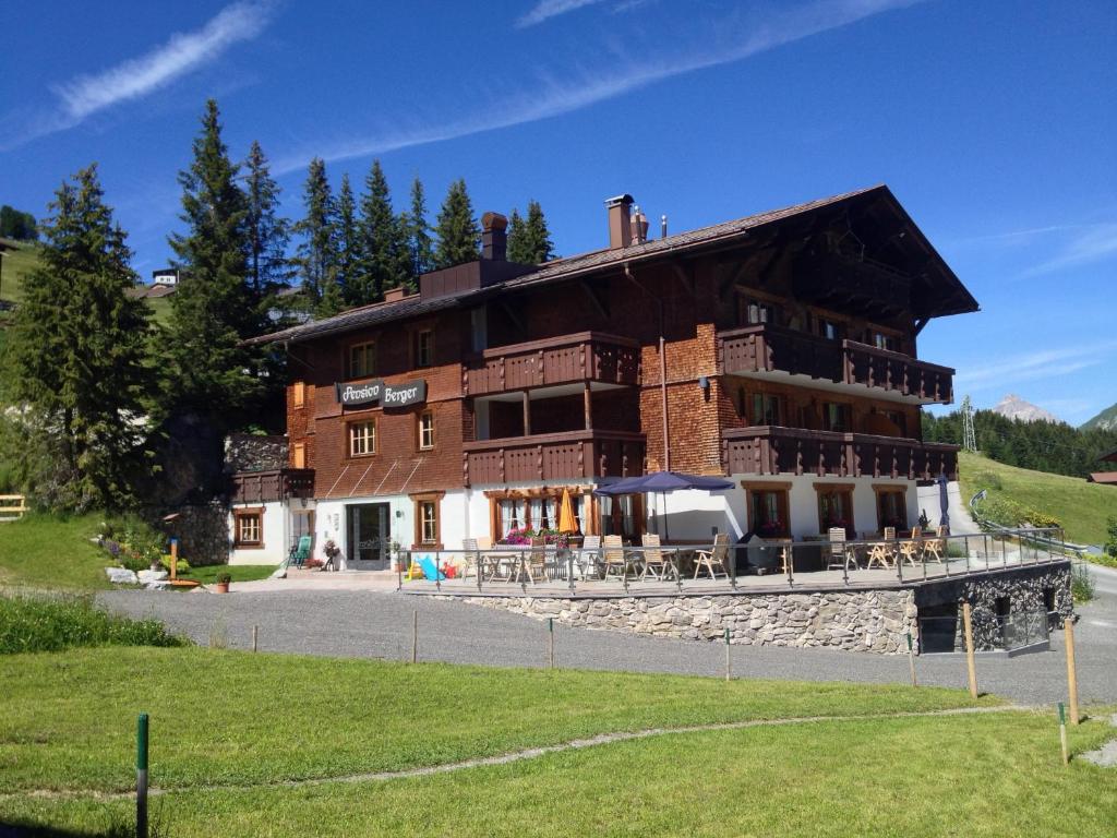 a large building with tables and chairs in front of it at Pension Berger in Oberlech