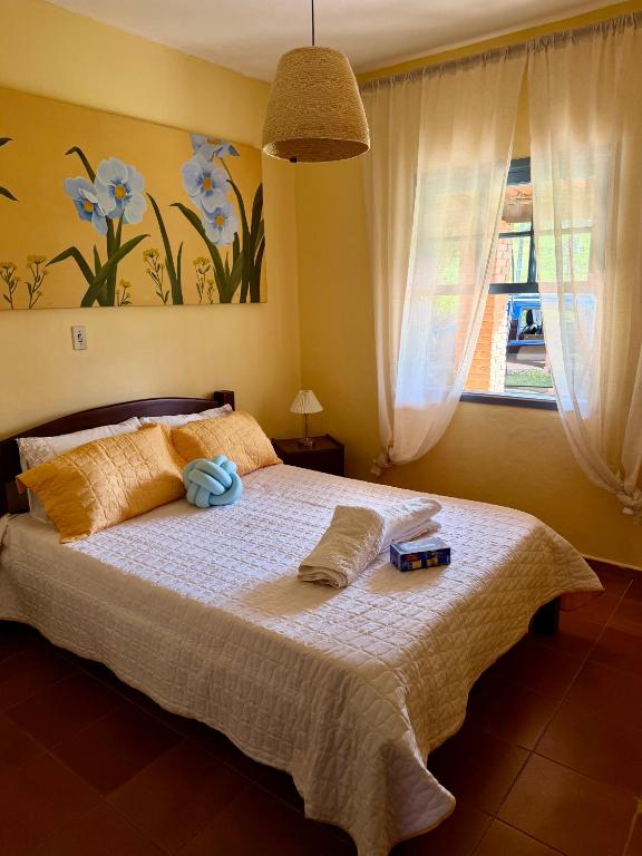 a bedroom with a bed with two pillows and a window at Sítio Toca da Pedra in Pedra Bela