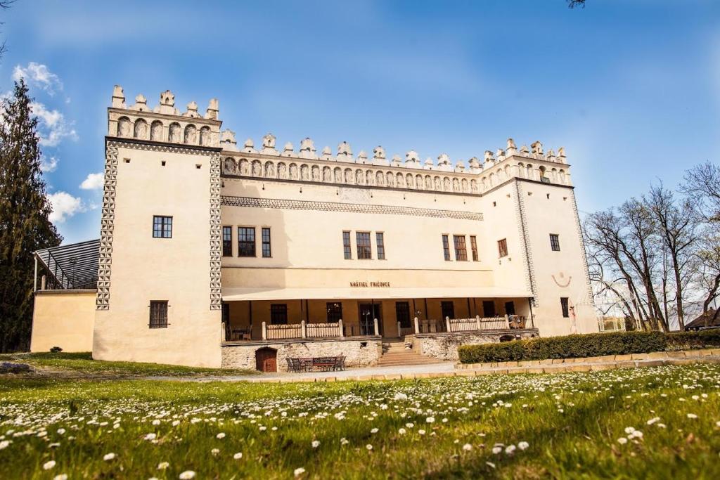 a large white building with a field of flowers at Kaštieľ Fričovce in Fričovce