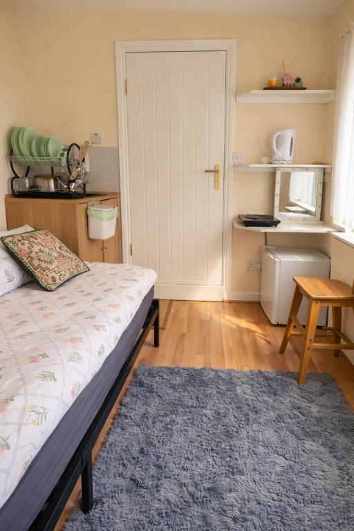 a bedroom with a bed and a table and a door at Heathrow Direct in Hillingdon