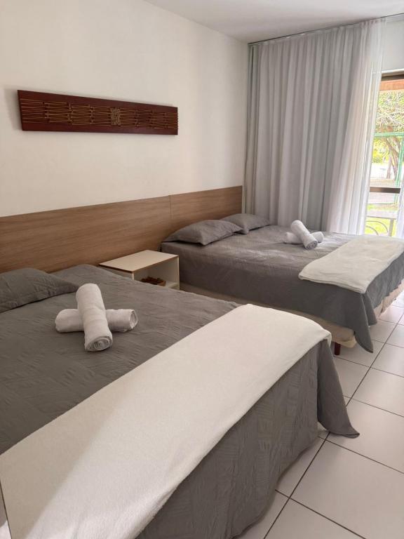 a bedroom with two beds and a window at Iloa Residence V13 Beach - localização privilegiada in Barra de São Miguel