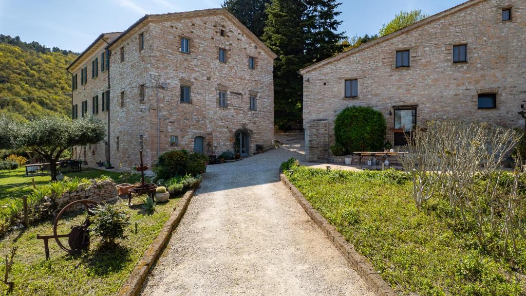 an external view of a large stone building with a pathway at Borgo Belfiore in Arcevia