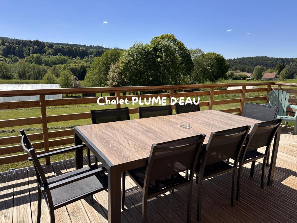 a wooden table and chairs on a deck at Chalet PLUME D'EAU - jacuzzi, piscine et pétanque in Gerbépal