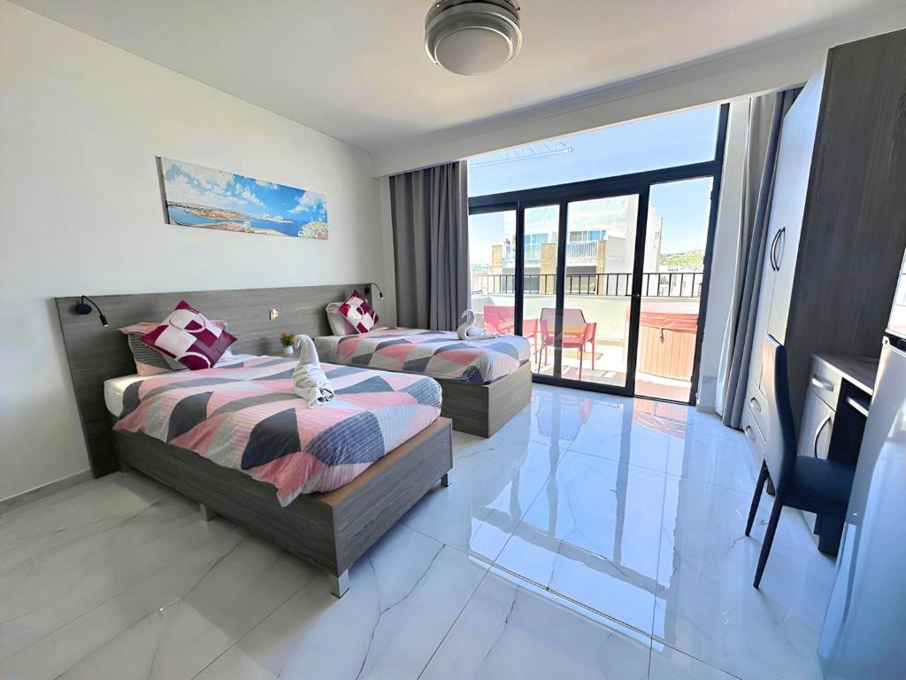 a hotel room with two beds and a balcony at For Rest Aparthotel in St. Paul's Bay