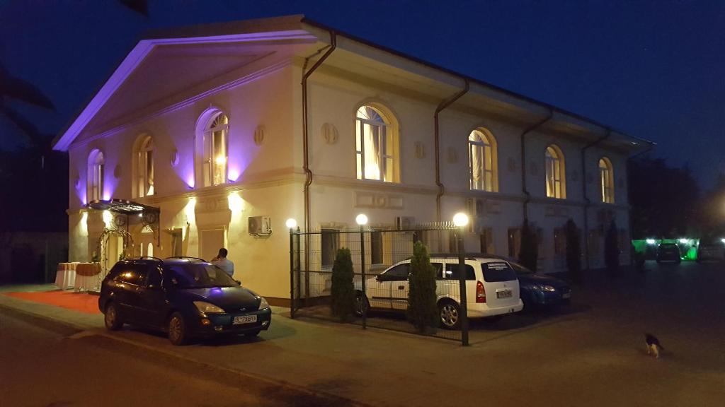 twee auto's geparkeerd voor een gebouw 's nachts bij Pensiunea Romeo Tecuci in Tecuci