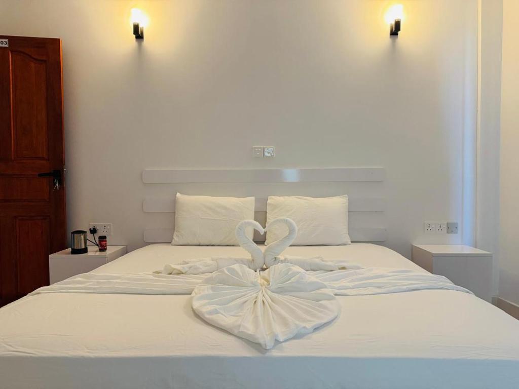 a white bed with a heart decoration on it at Rihiveli Palace in Maamigili