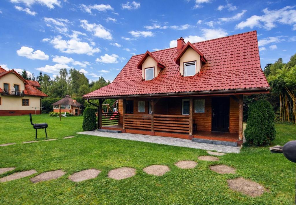 a wooden house with a red roof on a yard at Domki i Pokoje nad Soliną in Polańczyk