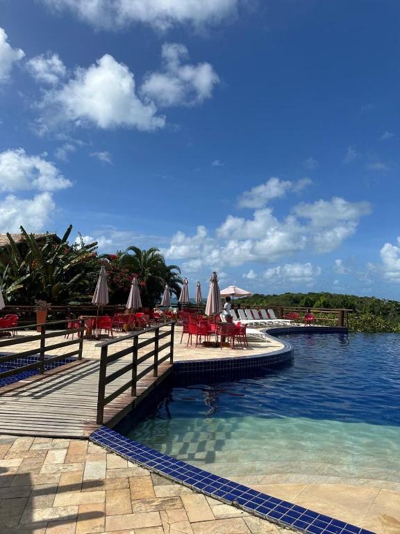 a resort with tables and chairs and the water at Bangalô com Quarto, Sala, Varanda in Maceió