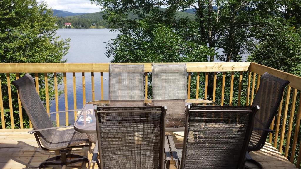 a table and chairs on a deck with a view of a lake at Chalet Le Pélican in Lac-Superieur