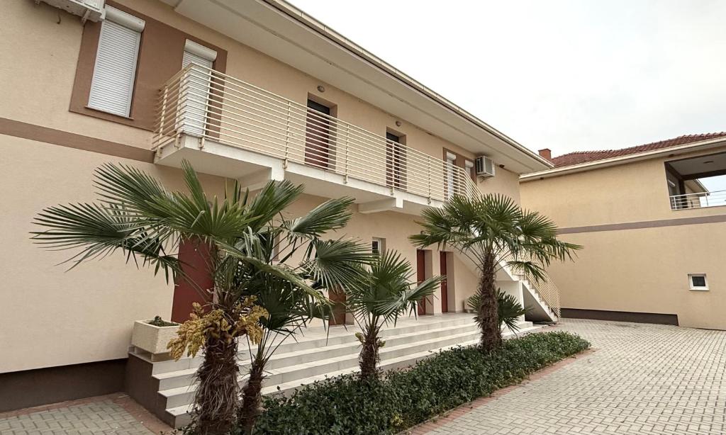 a building with palm trees in front of it at Nanchev Apartments in Gevgelija