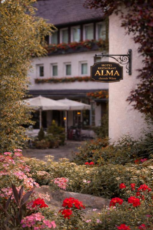 a hotel entrance with a sign for an inn with flowers at Hotel ALMA in Wassenberg