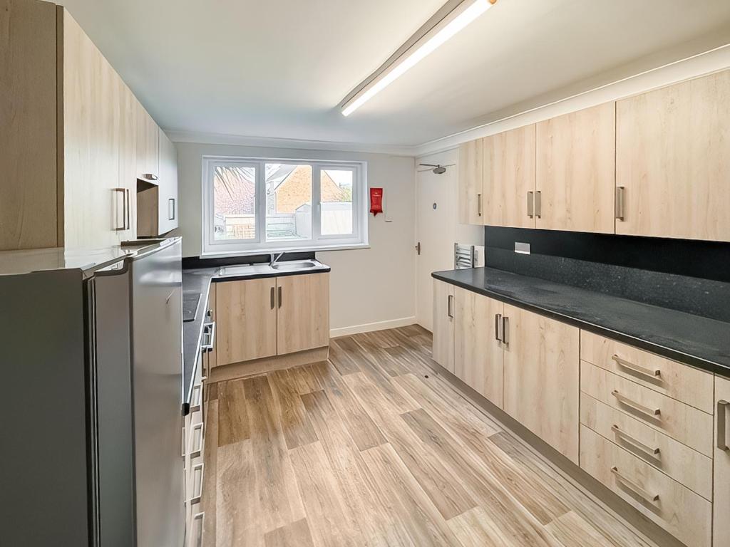 a kitchen with wooden cabinets and a refrigerator at Riverside Cottage in Spalding