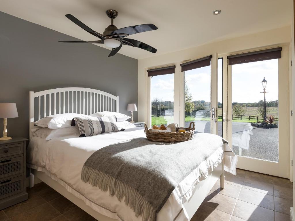 a bedroom with a bed with a fan and windows at Cow Pasture Cottage in Hallington