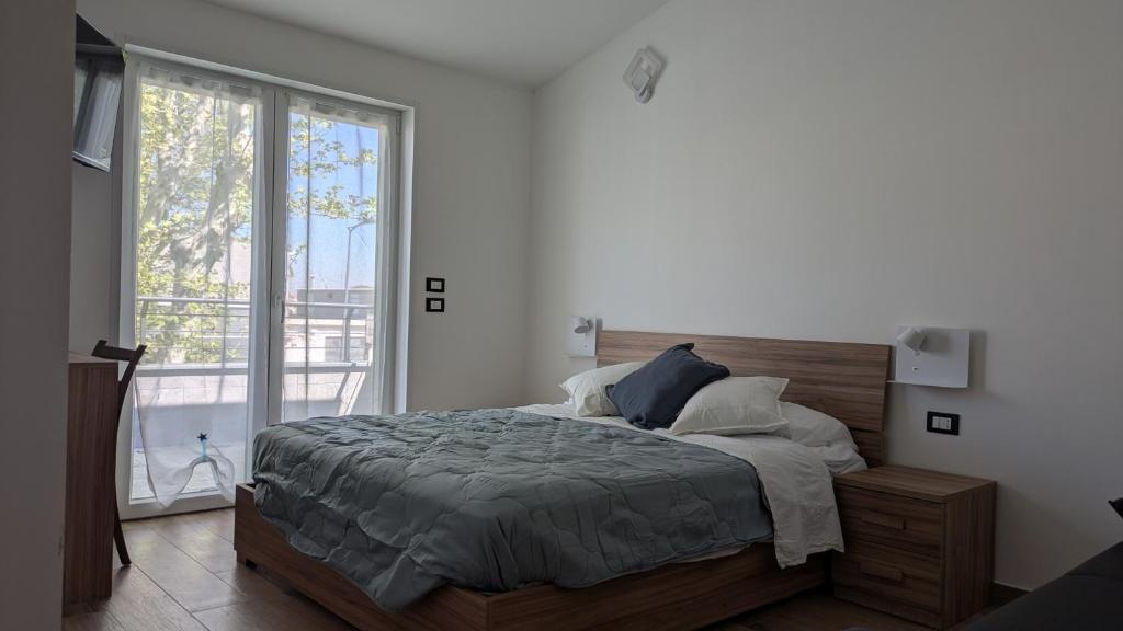 a bedroom with a bed and a large window at AURA MARINA - Guest House Fiumicino in Fiumicino