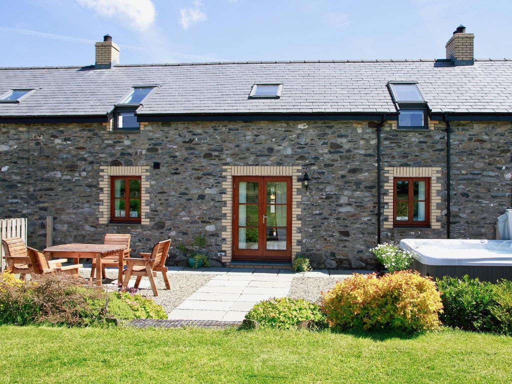 a stone house with a table and chairs in a yard at Bwthyn Onnen-Oa5 in Ystrad Meurig