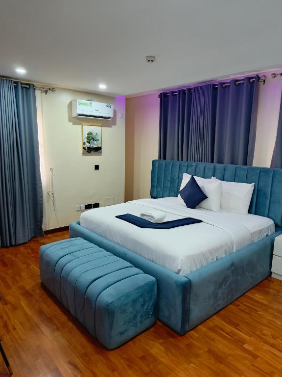a bedroom with a large bed with a blue tufted bed frame at Captain Residency Hotel in Lagos