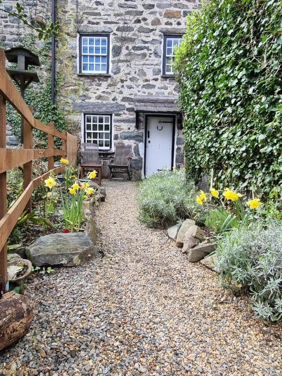 a stone house with a garden with yellow flowers at River Cottage in Llanbedr