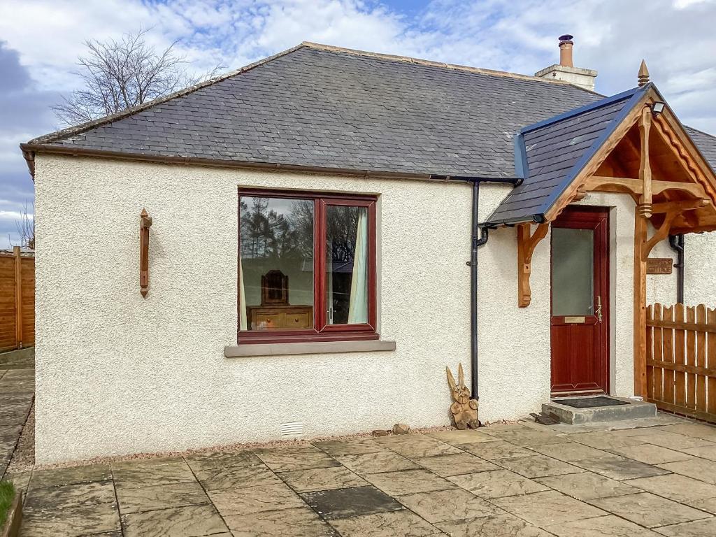 a small white house with a rabbit sitting outside at Keepers Cottage - Uk51549 in Kirktown of Auchterless