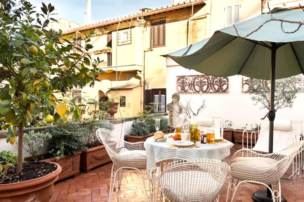 a patio with a table and chairs and an umbrella at Elegant Seafront Apartment in Ostia in Lido di Ostia