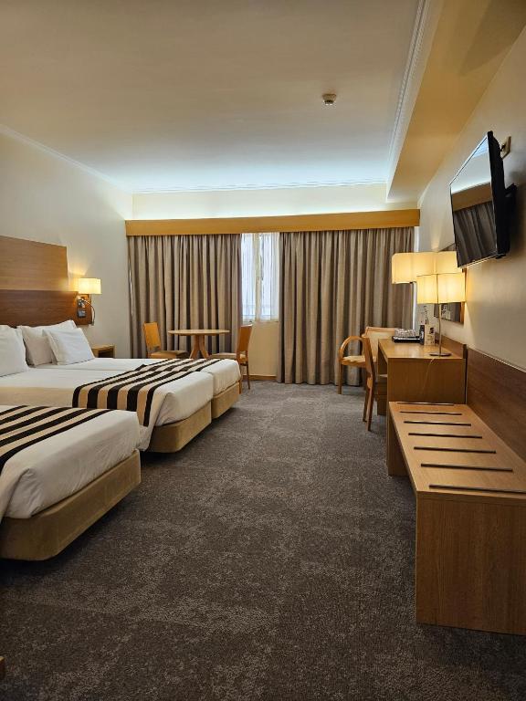a hotel room with two beds and a flat screen tv at Hotel Principe Lisboa in Lisbon