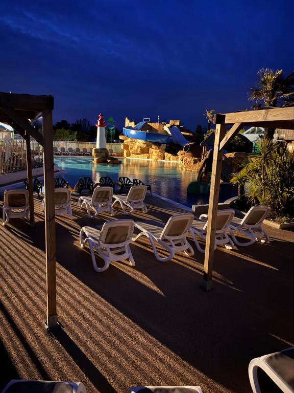 a group of chairs sitting on a deck near the water at mobil home spacieux climatisé sur camping sol a gogo in Saint-Hilaire-de-Riez