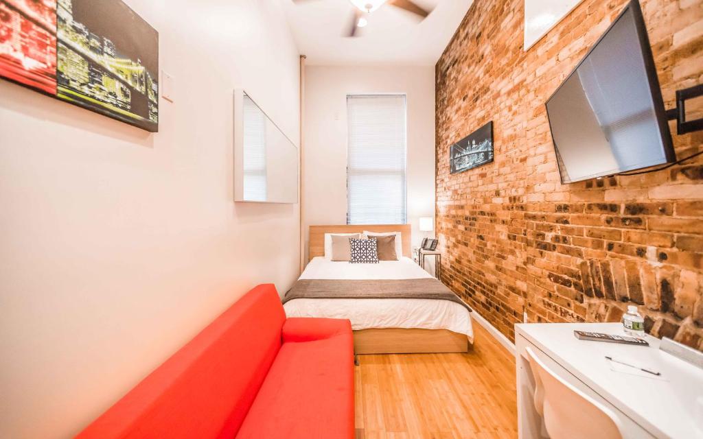 een kleine kamer met een bed en een bakstenen muur bij Chelsea Inn in New York