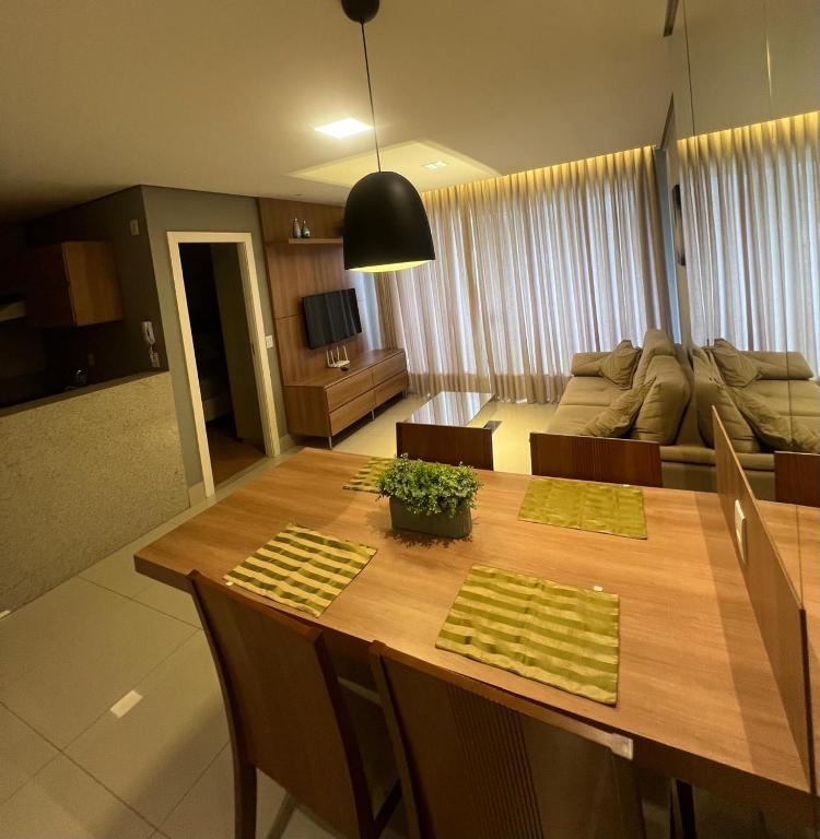 a living room with a wooden table and a couch at LRFlat - Ambiente climatizado, moderno, confortável e próximo a tudo! in Montes Claros