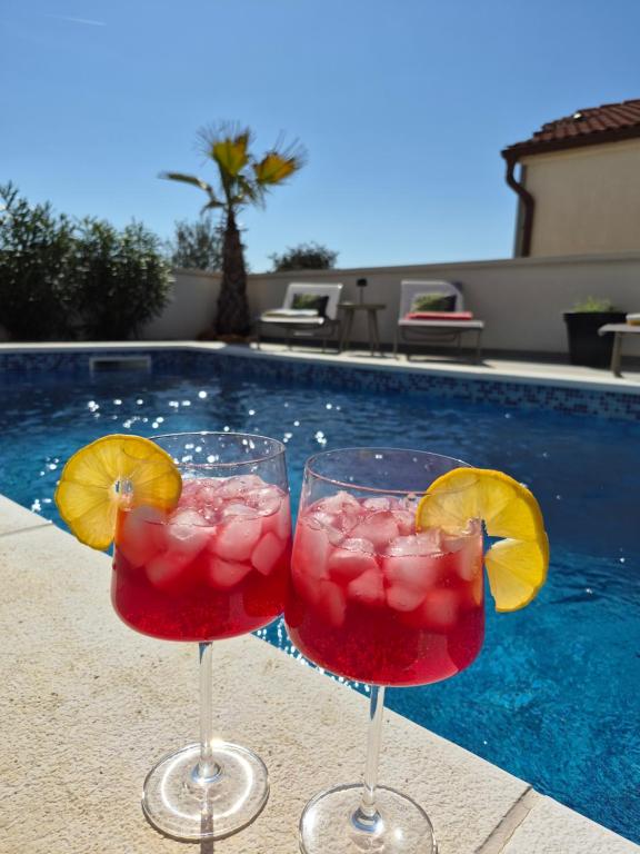 two cocktails in glasses next to a swimming pool at Vila VivaVir with 2x E-Scooter, private Pool & Grill in Vir