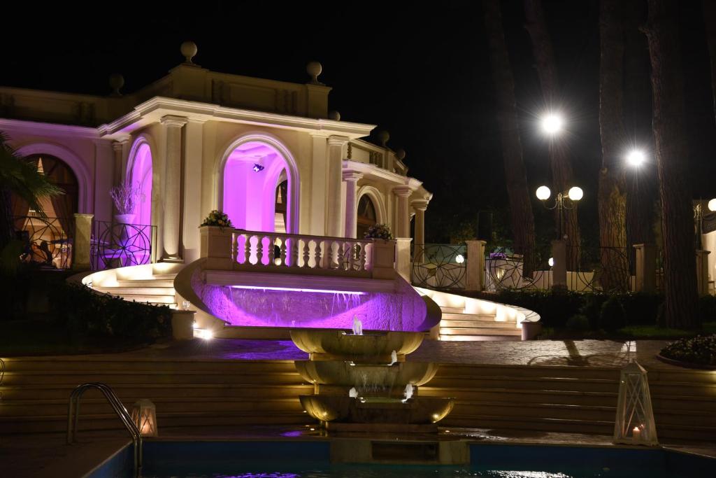 - un bâtiment avec une fontaine la nuit et des lumières violettes dans l'établissement Park Hotel Villaferrata, à Grottaferrata