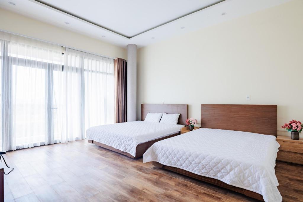 a bedroom with two beds and a large window at BEN Villa in Cẩm Phả Mines