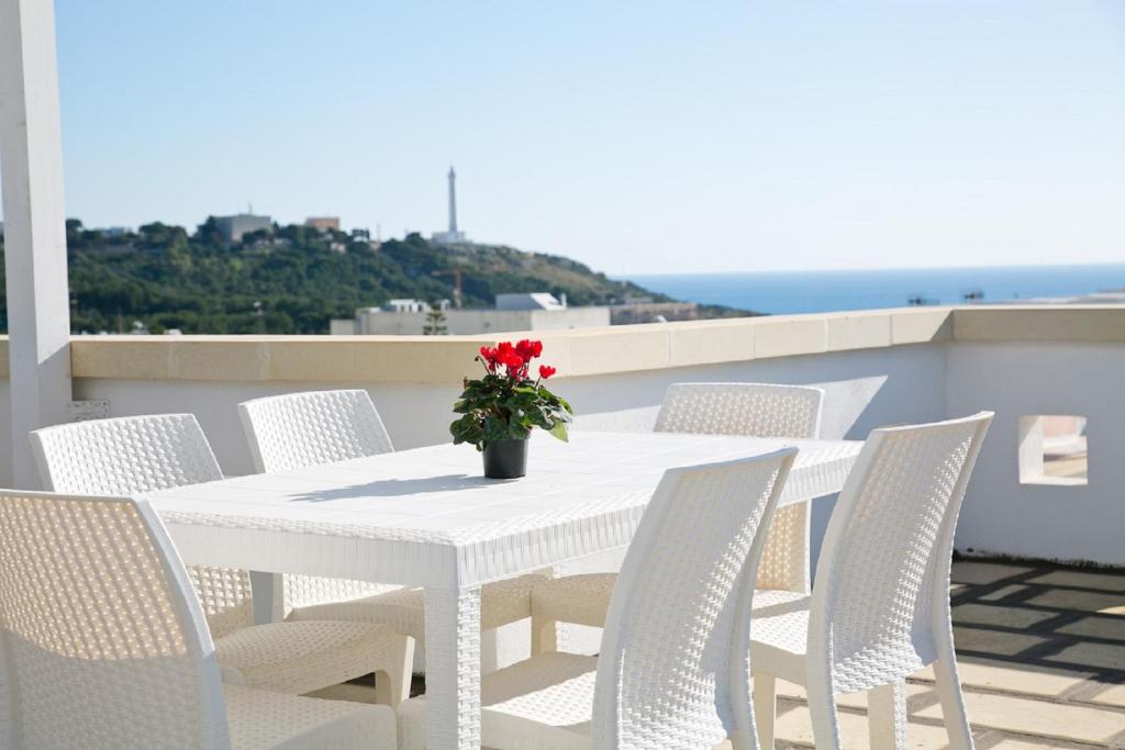 Residence Giuliana في ليوكا: طاولة بيضاء مع كراسي بيضاء و مزهرية مع زهور حمراء