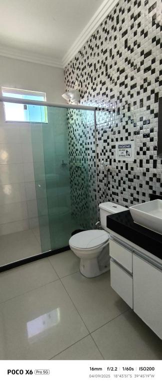 a bathroom with a toilet and a glass shower at Aconchegante in São Mateus