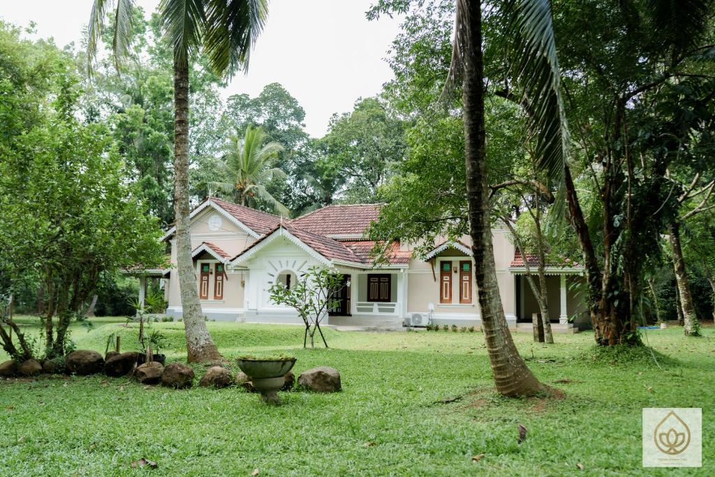 a white house with palm trees in front of it at Wimala Sewana in Veyangoda