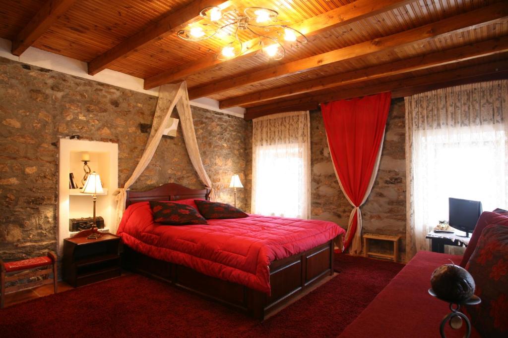 a bedroom with a red bed in a room with wooden ceilings at Elka in Palaios Agios Athanasios