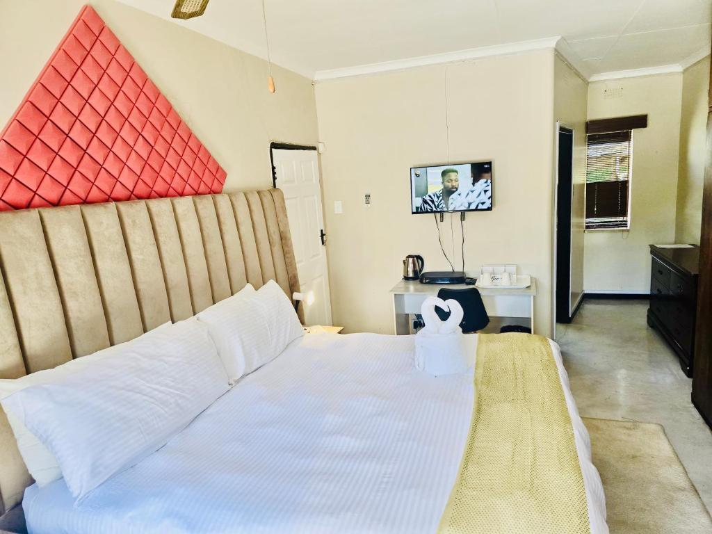 a bedroom with a white bed and a tv at SapzRes at Klerksdorp in Klerksdorp