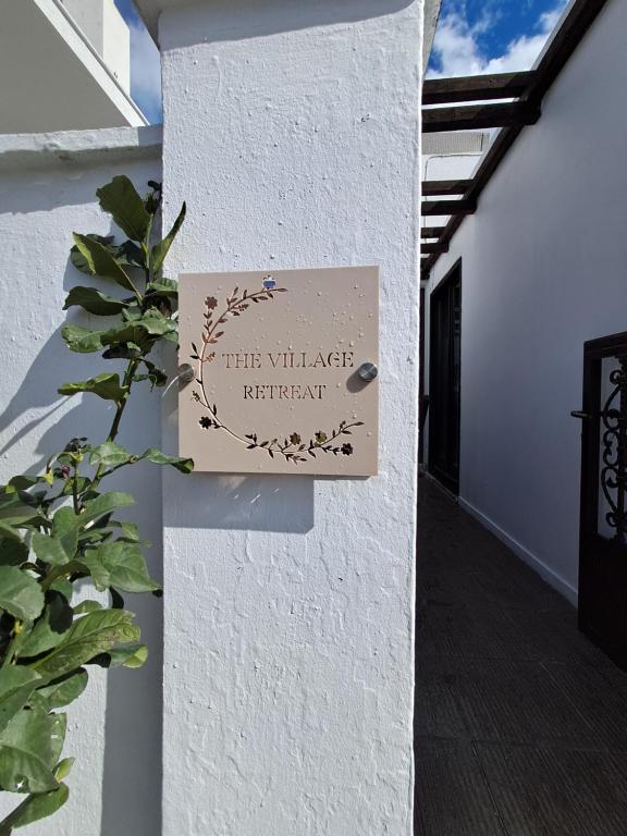 a sign on the wall of a white building at The Village Retreat in Malona Village