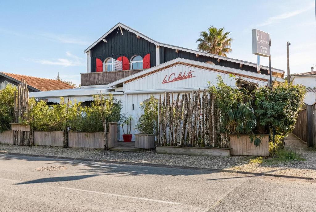 a white building with a fence in front of it at Hôtel Le Caillebotis in Cap-Ferret