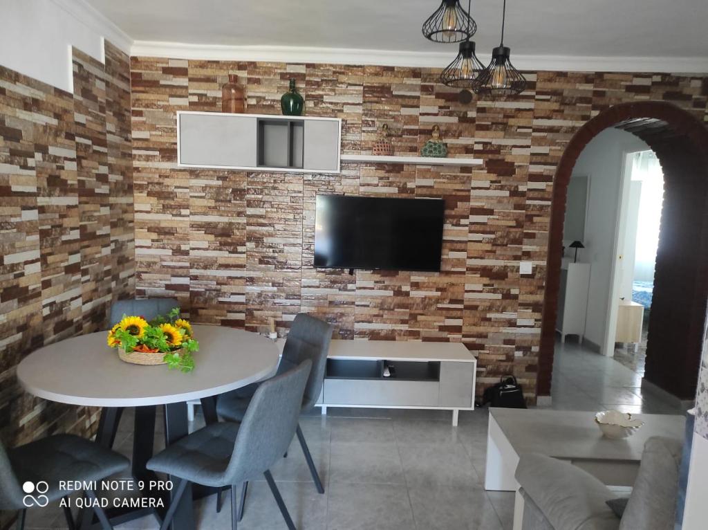 a living room with a table and a brick wall at Apartamento en Torrox in Torrox