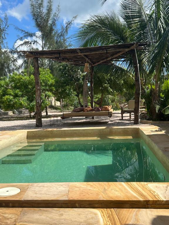 a swimming pool in a yard with a pergola at Uroa Sunset Bliss in Uroa